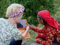 A Western Woman Shows an Elderly Asian Women a Tablet
