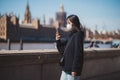 Young lady wearing medical mask taking pictures with phone at the Thames river embankment Royalty Free Stock Photo