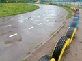 Wet asphalt jogging road turns to the left at the school stadium