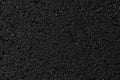 Wet asphalt texture, material. Black backdrop, grain pavement. Dark grunge surface, background.