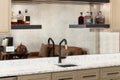 A wet bar with brown cabinets and a black and gold faucet.