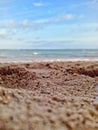 wet beach sand texture with bokeh background of sea waves and cloudy blue sky Royalty Free Stock Photo