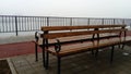 Wet bench on a foggy day. Metal curled wrought iron fence detail. Off-season melancholic mood Royalty Free Stock Photo