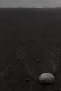 Wet black volcanic sand on shore with white stone, zen, texture, background, vertical. Royalty Free Stock Photo