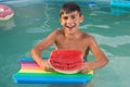 Wet boy in the pool with a swimming board, holds in his hands a piece of watermelon, emotions, summer vacation concept