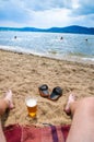 Wet boys feet on beach and sand with cup of beer Royalty Free Stock Photo