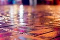 Wet brick sidewalk reflecting multicolored lights on a rainy night Royalty Free Stock Photo