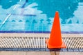 wet bright orange cone placed by the swimming pool side as safety precaution sign