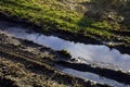 Wet brown mud with car tyre tracks, puddles in tire tracks tafter heavy rain in spring Royalty Free Stock Photo