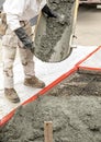 Wet cement off loaded by a construction worker from a cement truck chute into a concrete form