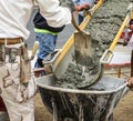 Wet cement off loaded by construction workers from a cement truck chute into a wheelbarrow