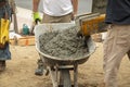 Wet cement off loaded by construction workers from a cement truck chute into a wheelbarrow