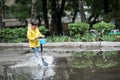 A wet child is jumping in a puddle. Fun on the street. Tempering in summer Royalty Free Stock Photo