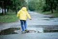 A wet child is jumping in a puddle. Fun on the street. Tempering in summer