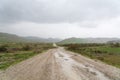 Wet dirt road leading to the mountains Royalty Free Stock Photo