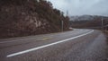 Wet empty tarmac road turn mountain track on a rainy foggy winter scene