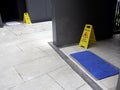 Wet floor caution sign on walkway near the building after raining. Royalty Free Stock Photo