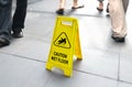 Wet floor sign with people walking in background Royalty Free Stock Photo