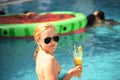 Wet girl emerged from the water drinks orange fresh by the pool. natural girl without glamorous processing. Royalty Free Stock Photo