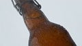 Wet glass beer bottle covered moisture droplets on white background close up. Royalty Free Stock Photo