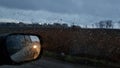 Shot through wet car window with side mirror in fall rainy weather Royalty Free Stock Photo