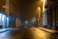 A wet high street with historic buildings with street lights glowing on a misty winters night. Upton Upon Severn, UK