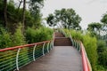 Wet hillside planked walkway with colorful railings in cloudy summer
