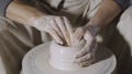 Wet male potter& x27;s hands sculpting soft clay and shaping the pot on potters wheel. Master gives shape to the pottery Royalty Free Stock Photo