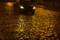 Wet night golden color pavement in the light of a passing car
