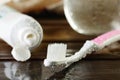 wet pink Toothbrush and open tube of toothpaste on a wooden table horizontal