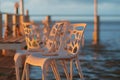 Wet plastic chairs after the rain on the shore illuminated by the sunset light