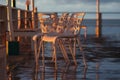 Wet plastic chairs after the rain on the shore illuminated by the sunset light