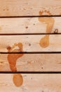 Wet prints of two human feet on brown wooden deck floor. Close up Royalty Free Stock Photo