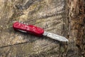 Wet red pocket knife lying on wooden table
