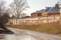 A wet road going down, an old brick wall and roofs of houses on the hill behind. Royalty Free Stock Photo