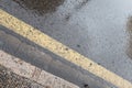 Wet road on a rainy scene with yellow diagonal line crossing still