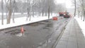 On the wet roadway of the city street, the asphalt pavement is being patching and a tractor and dump truck are being used. Areas o Royalty Free Stock Photo