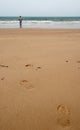 Wet sand beach with footprints and a remote man