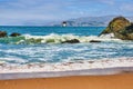 Wet sandy beach with incoming wave and abandoned lighthouse structure in ocean