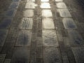 The wet, shiny stone pavement is laid in rows of rectangular tiles. The sidewalk moves forward in perspective. Royalty Free Stock Photo