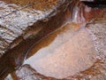 Red granite stones by flowing water over it. Royalty Free Stock Photo