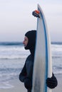 Wet surfer with surfboard standing on the sand