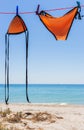 Wet swimsuit on the rope with pins on the beach. Orange swimsuit dried on clothesline on seascape background. Summer fashion. Royalty Free Stock Photo