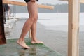 A wet undressed man legs stands near a hole in the winter Royalty Free Stock Photo