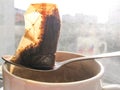 Wet used disposable tea bag on a metal spoon lying on a white dirty ceramic cup in the backlight from the window Royalty Free Stock Photo