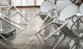 Wet white plastic chairs with raindrops in a street cafe, overturned, after a rain in Italy, in the evening Royalty Free Stock Photo