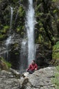 Wet young man posing in front of a waterfall