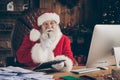 Whait if i. Thoughful minded santa claus sit table prepare x-mas christmas gift order write clipboard think thoughts