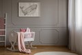 Whale on poster on the empty grey wall of cute baby bedroom interior with white cradle with pillow and paste pink blanket Royalty Free Stock Photo