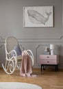 Whale on poster in baby room with white rocking chair and pastel pink nightstand with books and lamp Royalty Free Stock Photo